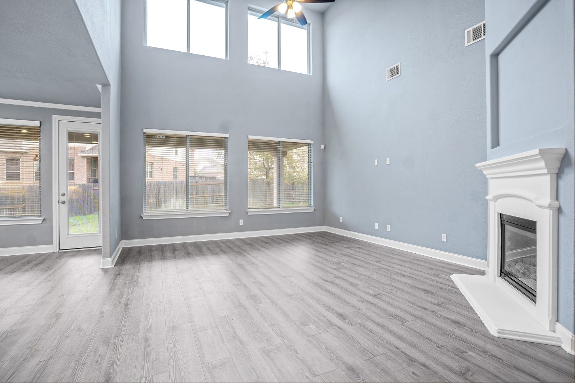 2328 Blended Tree Ranch Drive Leander, TX 78641 - Photo 9 of 30 an empty room with wooden floor fireplace and windows
