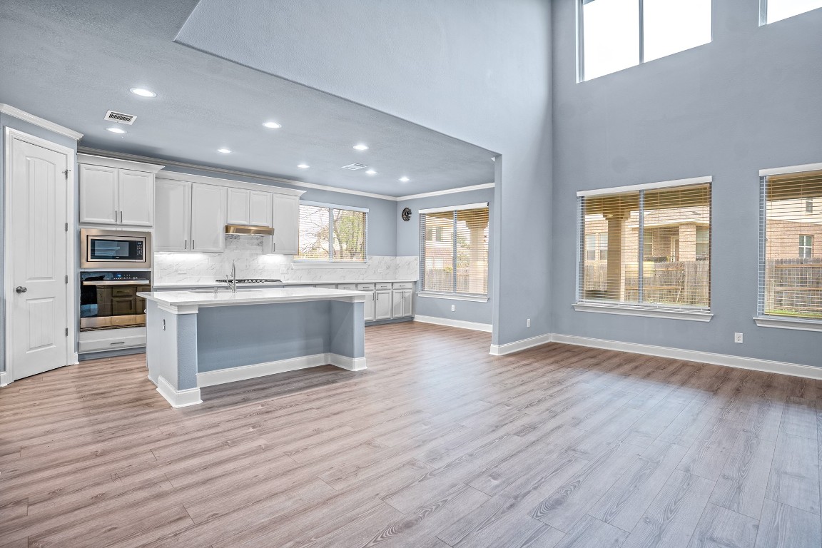 2328 Blended Tree Ranch Drive Leander, TX 78641 - Photo 10 of 30 a room with stainless steel appliances kitchen island wooden floor and large window