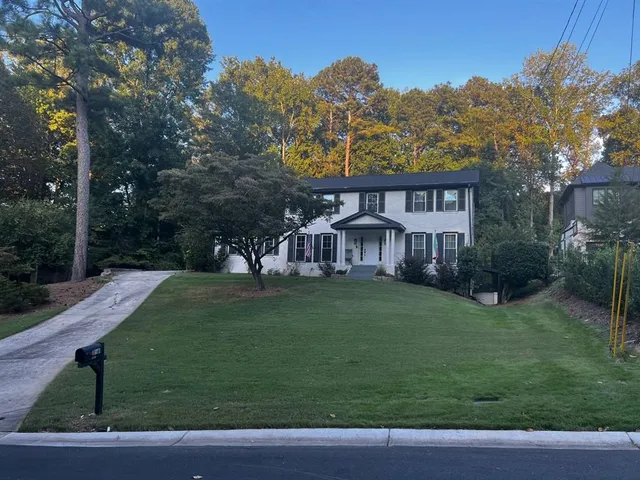 a view of a big house with a big yard and large trees