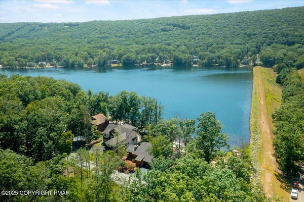 an aerial view of a houses with a yard and lake view