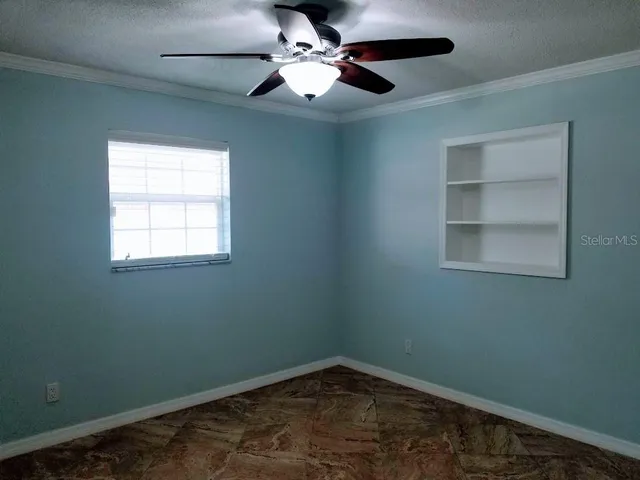 an empty room with a window and a fan