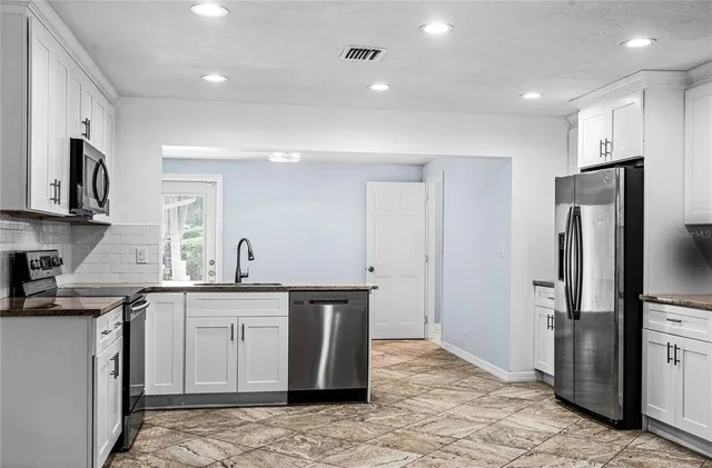 a kitchen with stainless steel appliances granite countertop a sink a stove a refrigerator and cabinets