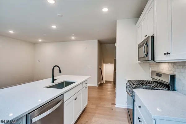 a kitchen with white cabinets a sink and appliances