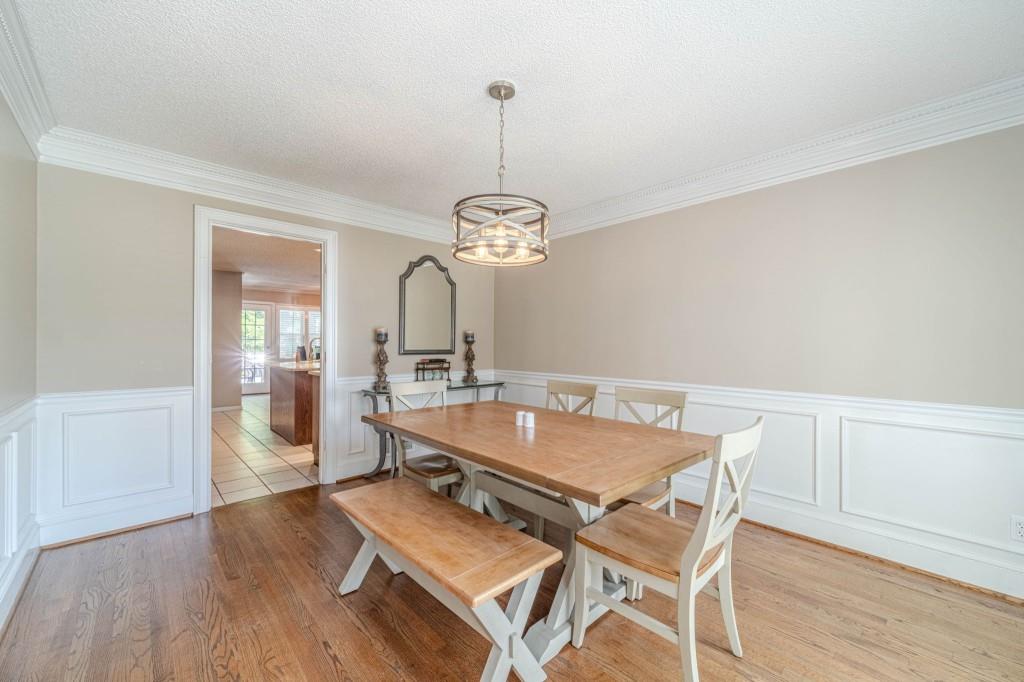 816 McDaniel Street Monroe, GA 30655 - Photo 9 of 52 a dining room with wooden floor a chandelier a wooden table and chairs