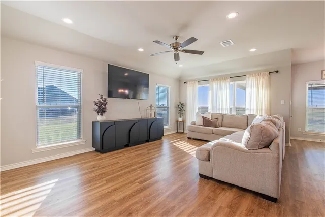 a living room with furniture a flat screen tv and a ceiling fan