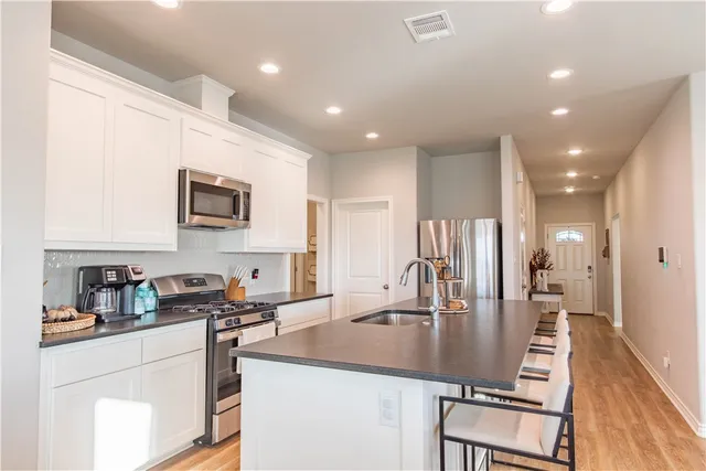 a kitchen with counter top space a sink wooden cabinets and stainless steel appliances