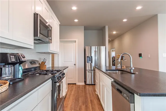 a kitchen with stainless steel appliances granite countertop a table chairs refrigerator and microwave