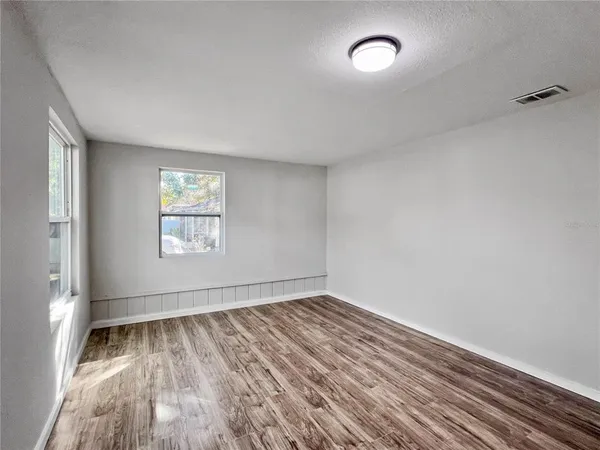 an empty room with wooden floor and windows