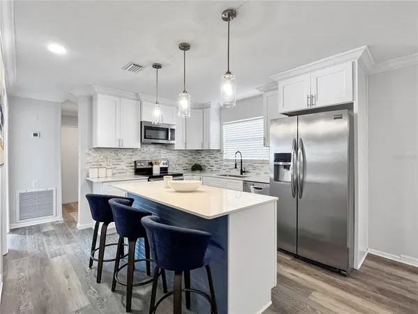 a kitchen with stainless steel appliances granite countertop a sink a stove a refrigerator and island with wooden floor