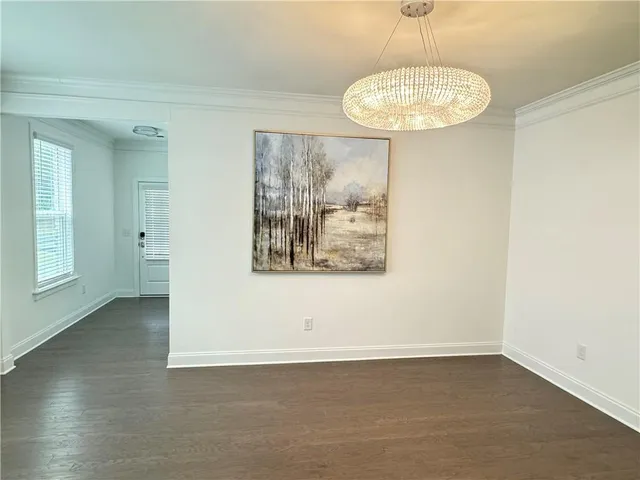 an empty room with a chandelier fan and windows