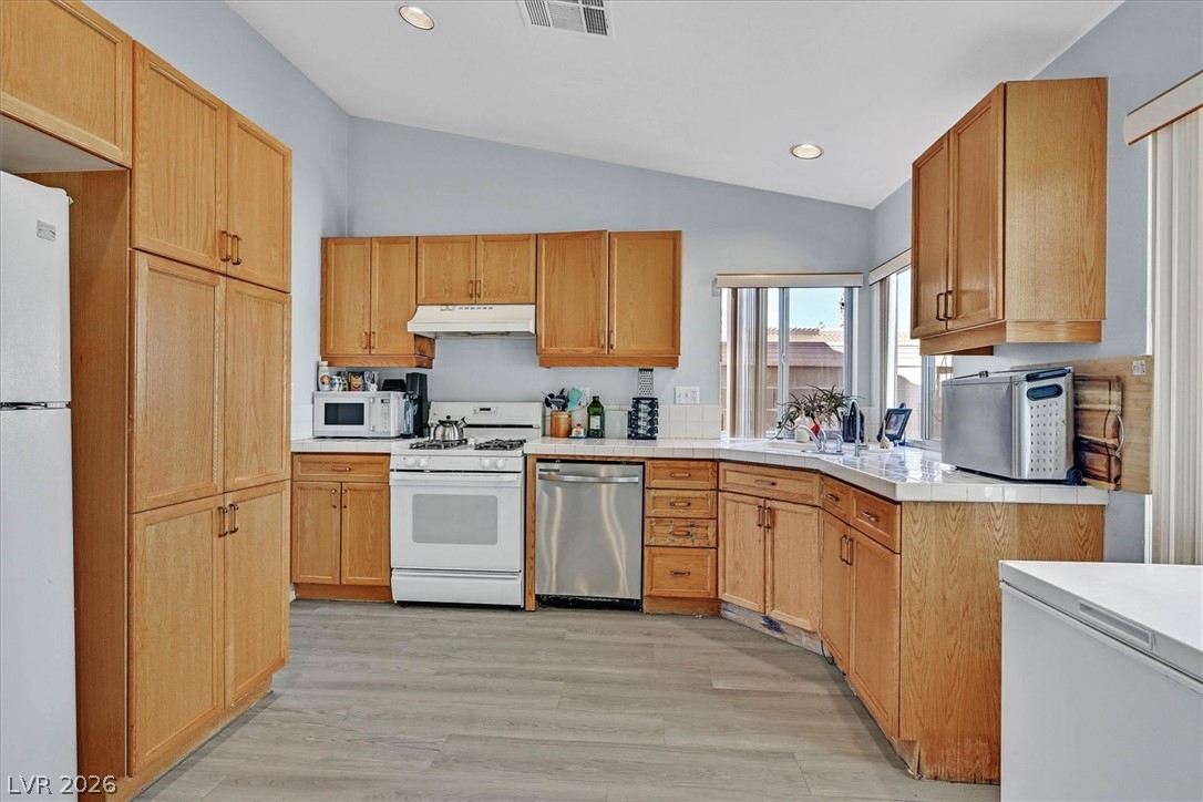 8830 Haviland Road Las Vegas, NV 89123 - Photo 12 of 43 Vaulted ceilings and warm wood cabinetry define this functional, light-filled kitchen space.