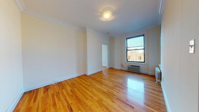 a view of empty room with window and wooden floor