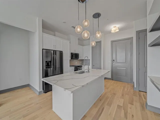 a large kitchen with stainless steel appliances a large center island attached withe living room