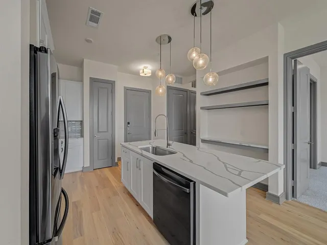 a view of a kitchen island a sink stainless steel appliances and cabinets