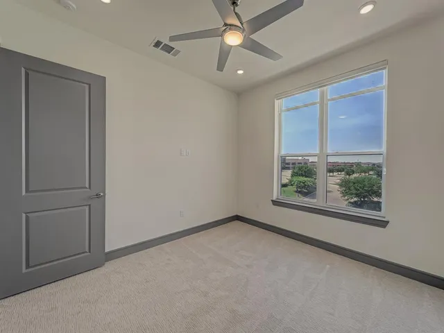 an empty room with a window and a ceiling fan