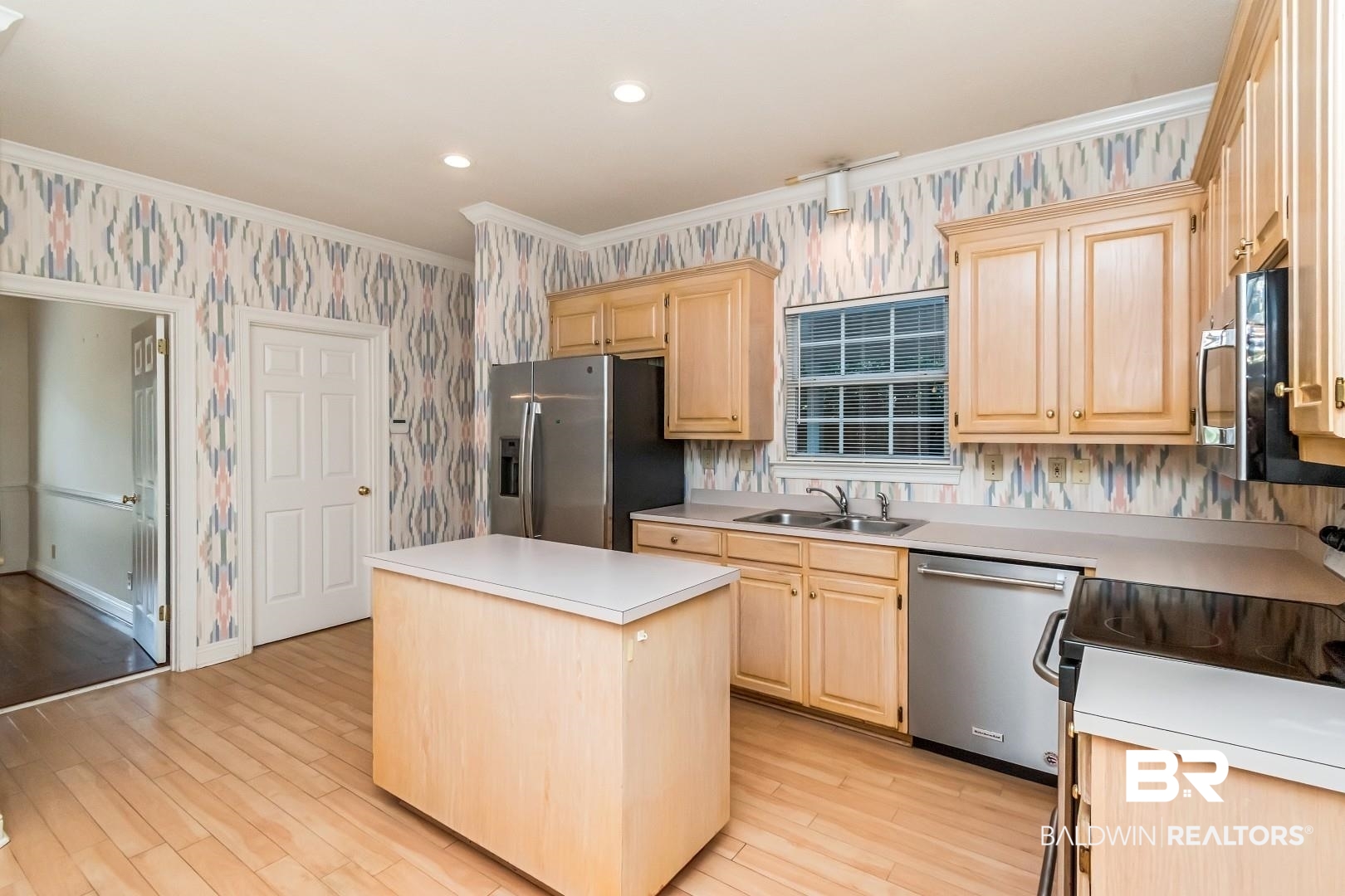 105 McHugh Lane Mobile, AL 36608 - Photo 11 of 30 Kitchen with light brown cabinets, wallpapered walls, a kitchen island, stainless steel appliances, and crown molding