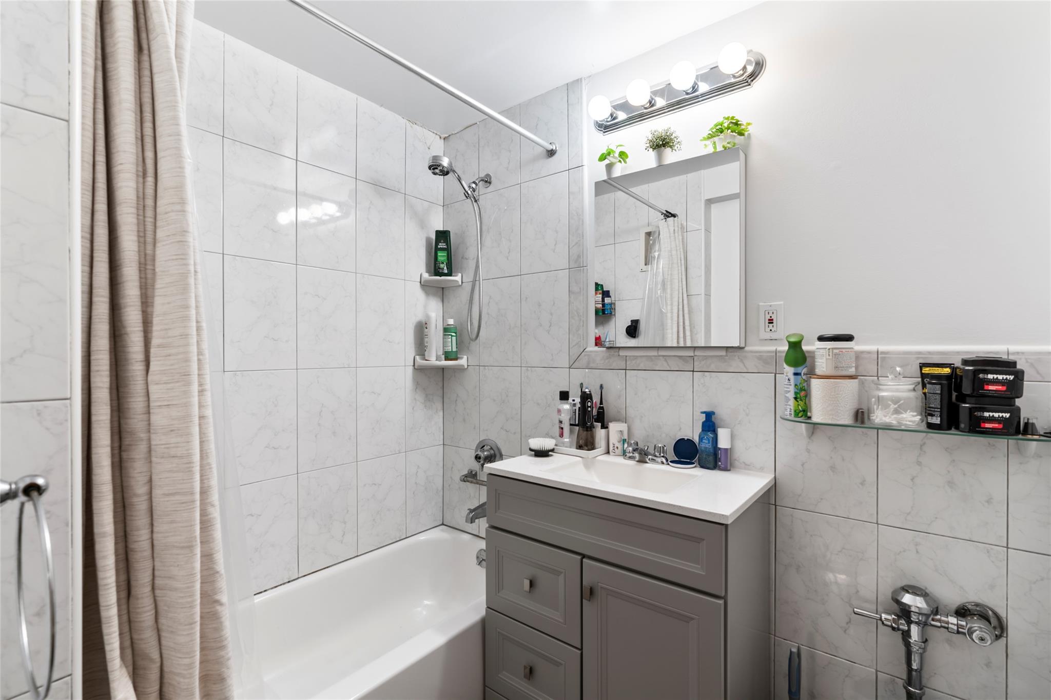 88-12 151st Avenue, Unit 4B Queens, NY 11414 - Photo 9 of 17 a bathroom with a sink vanity granite tub shower and a mirror