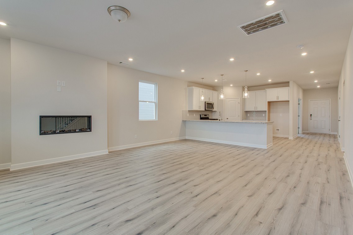 1310 Kristopher Drive Lebanon, TN 37087 - Photo 15 of 36 a view of an empty room with wooden floor and a kitchen