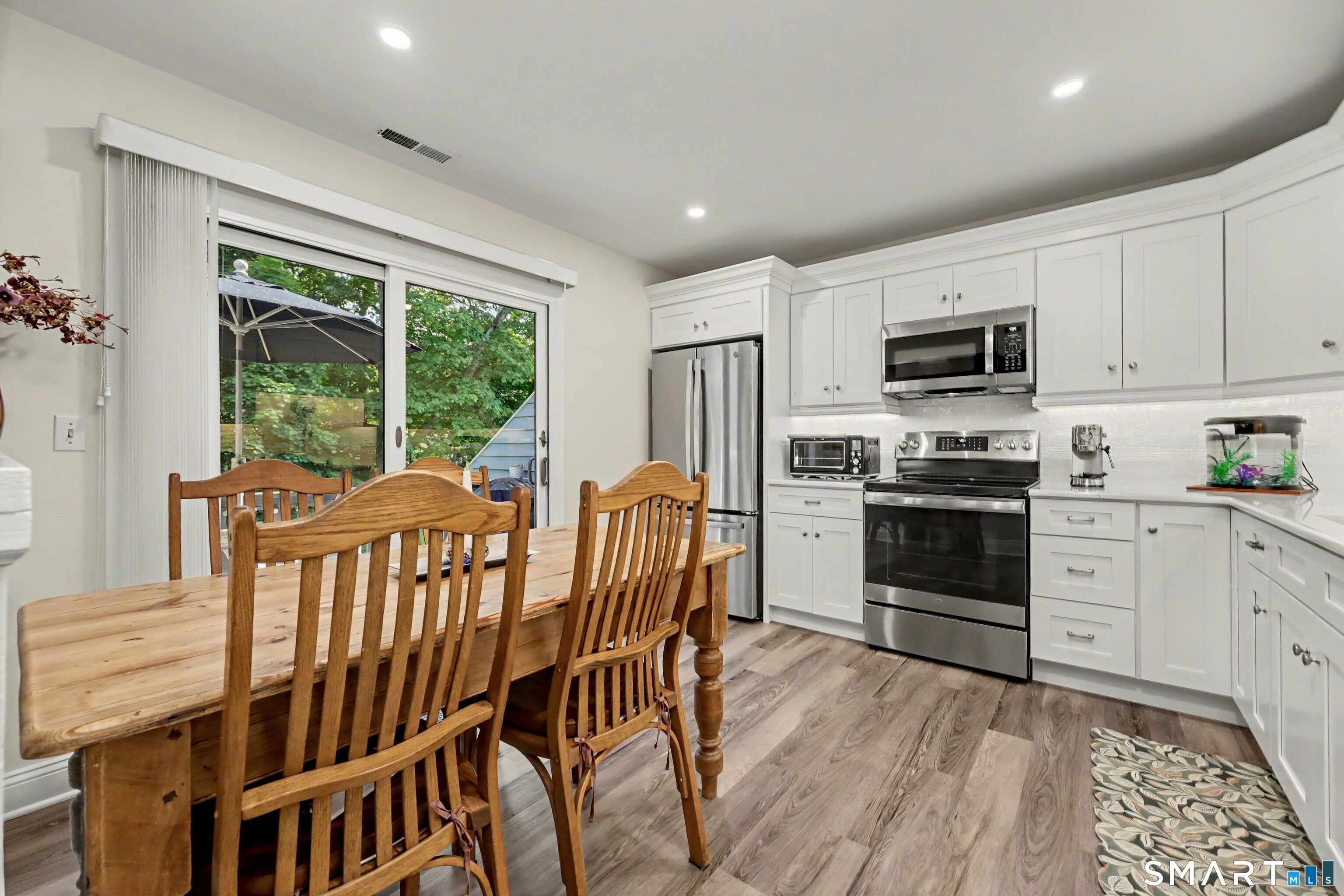 70 Fawn Ridge Lane, Unit 70 Norwalk, CT 06851 - Photo 10 of 36 a kitchen with stainless steel appliances granite countertop a stove top oven a sink dishwasher a dining table and chairs with wooden floor