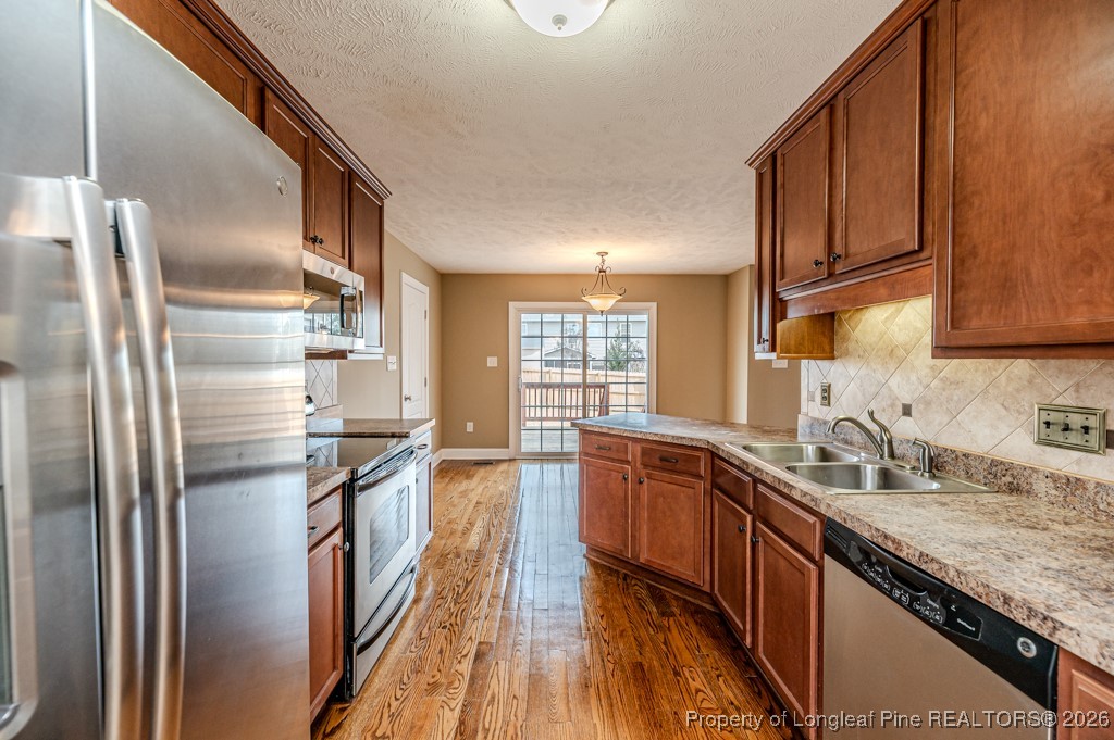 255 Trenton Place Cameron, NC 28326 - Photo 14 of 49 a kitchen with stainless steel appliances granite countertop a refrigerator a sink dishwasher a stove with wooden cabinets and floor