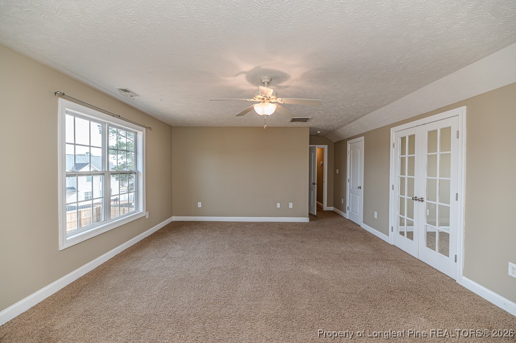 255 Trenton Place Cameron, NC 28326 - Photo 18 of 49 an empty room with chandelier fan and windows