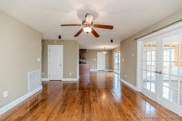a view of empty room with wooden floor and fan