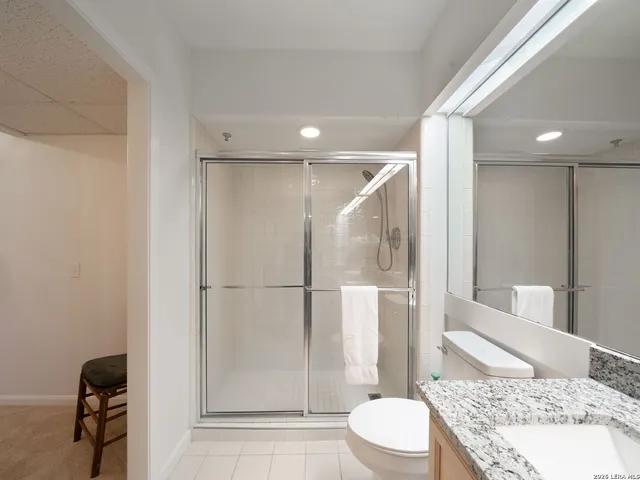 a spacious bathroom with a granite countertop sink toilet a mirror and shower