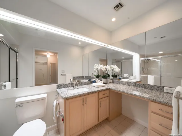 a bathroom with a granite countertop sink a toilet and a mirror