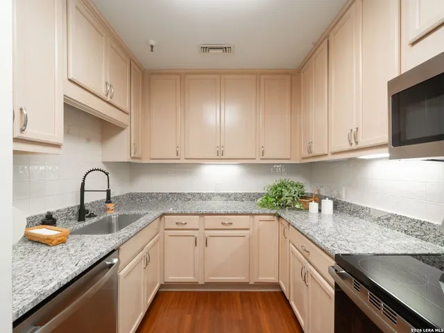 a kitchen with granite countertop white cabinets and a sink