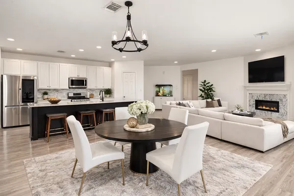 a dining room with furniture a chandelier a kitchen and a chandelier