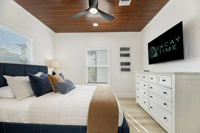a bedroom with a bed and a flat tv screen on dresser