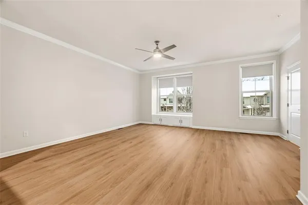 an empty room with wooden floor chandelier fan and windows