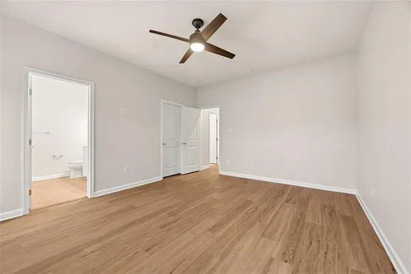 an empty room with wooden floor and a ceiling fan