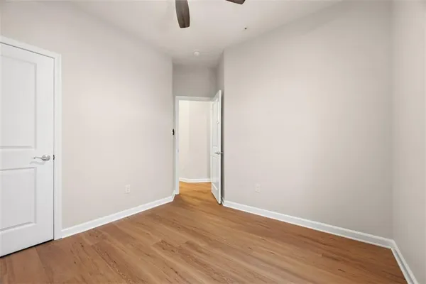 an empty room with wooden floor and fan