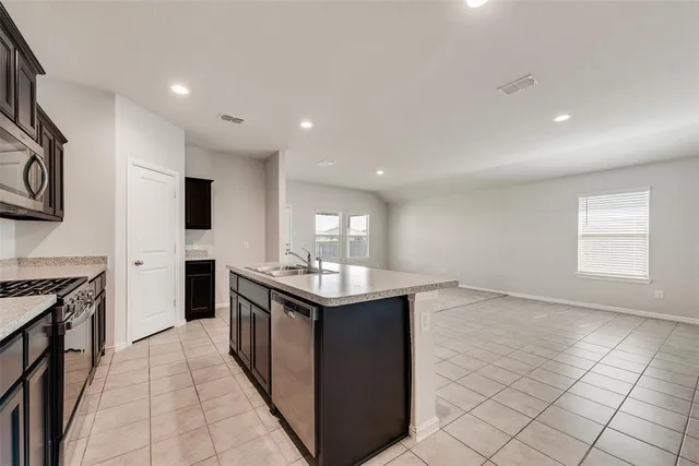 a view of a electric appliances in kitchen and empty room with wooden floor