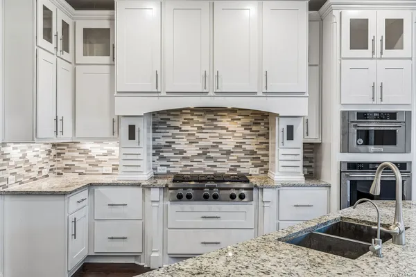 a kitchen with granite countertop a stove sink and cabinets
