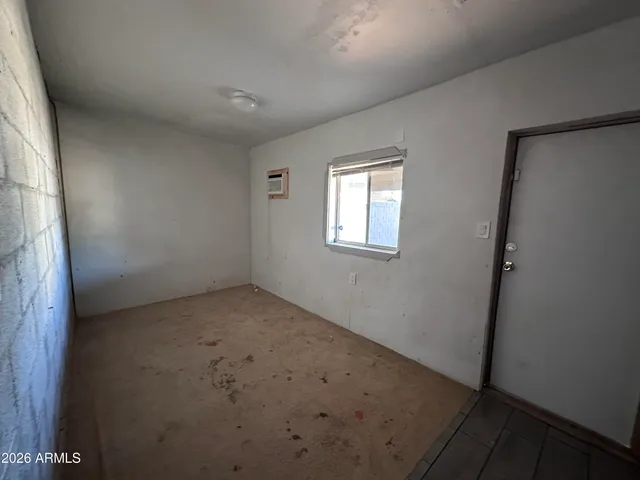 a view of an empty room with wooden floor and a ceiling fan