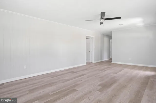 an empty room with wooden floor ceiling fan and windows