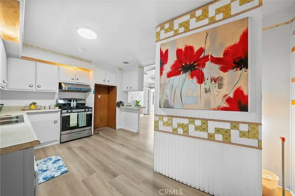 a kitchen with stainless steel appliances white cabinets and wooden floor