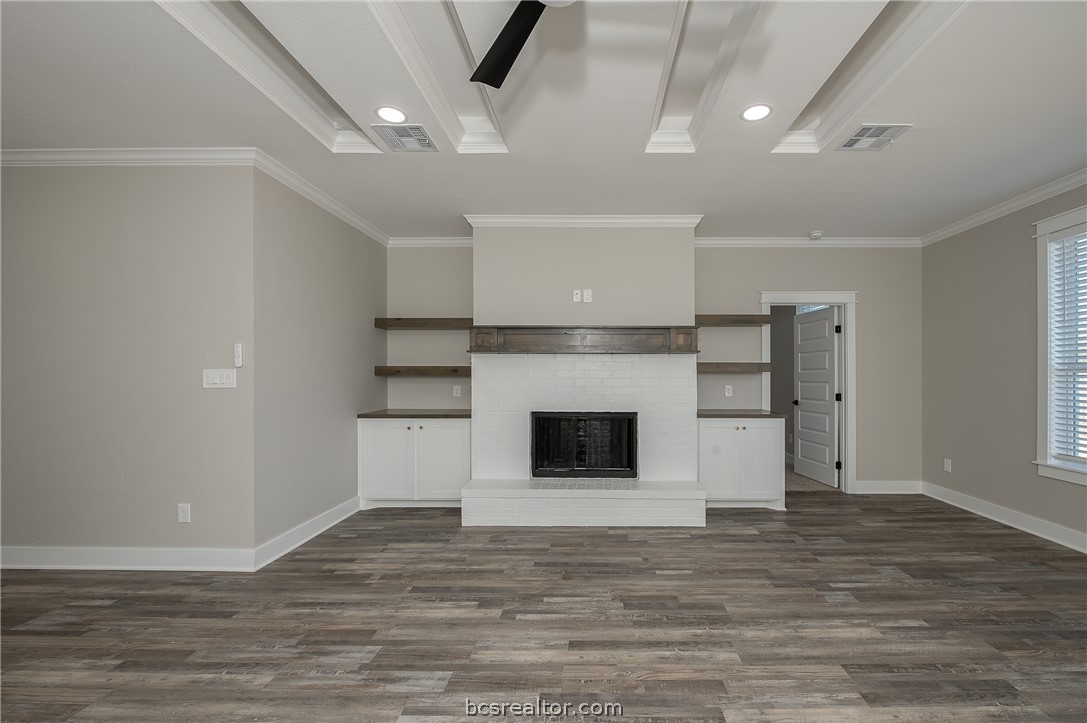 2908 GOLDBERG Drive Bryan, TX 77808 - Photo 26 of 44 View of the family room into the kitchen, decorative cove lighting, ceiling fan with lite kit, can lights, gas fireplace, and wood mantle, floating shelves, pop up ceilings and vinyl flooring.