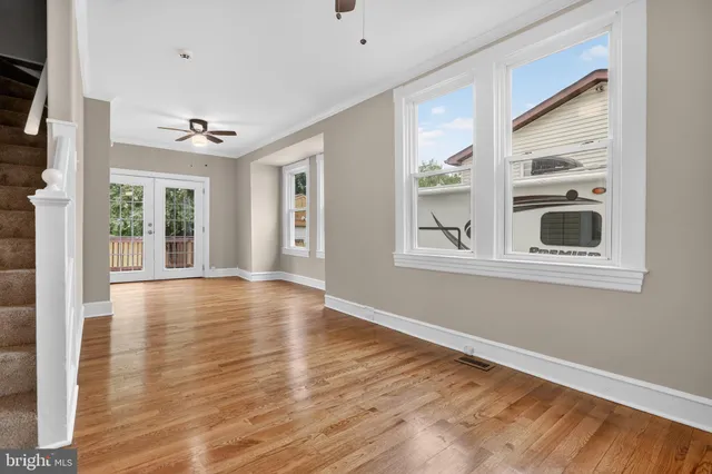 a view of an empty room with a window and wooden floor