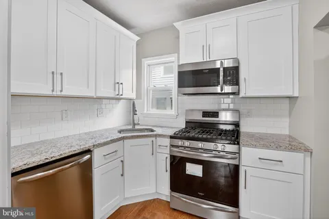 a kitchen with granite countertop a stove top oven microwave and cabinets