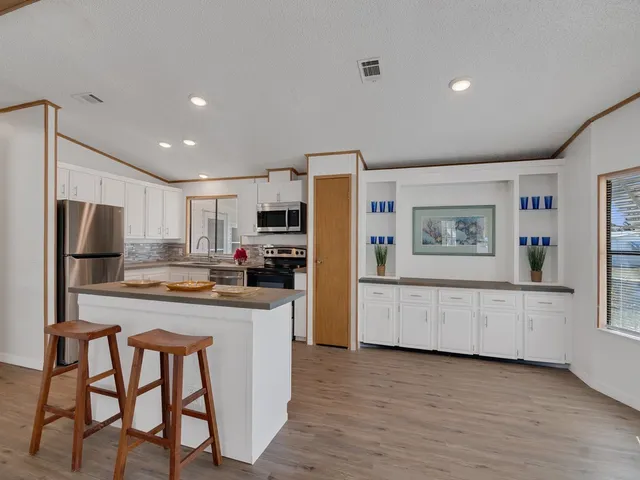 a kitchen with stainless steel appliances granite countertop a refrigerator and a stove top oven