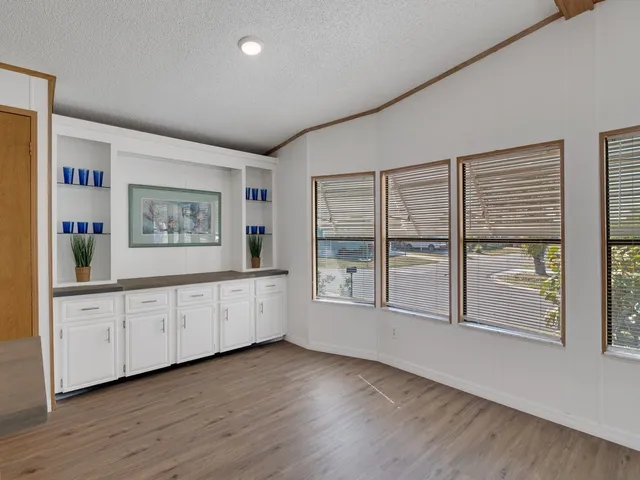 a view of an empty room with wooden floor and a ceiling fan