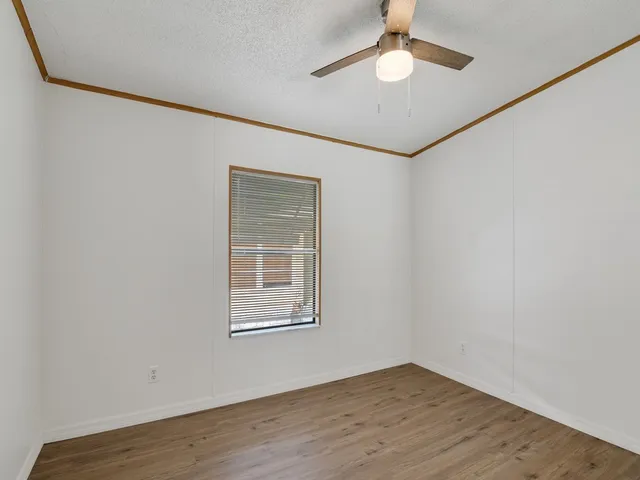 an empty room with wooden floor closet and windows