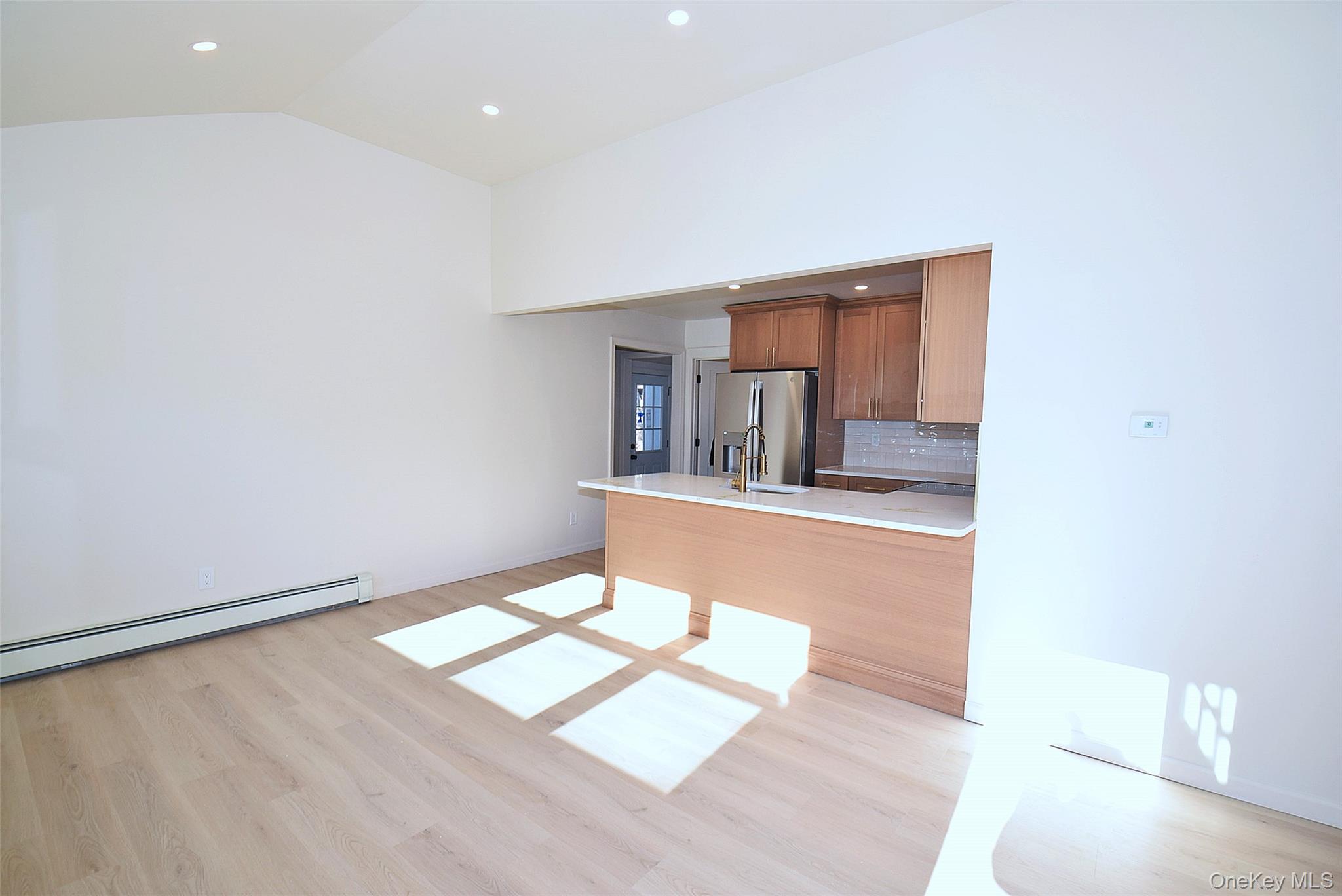 371 Oceanside Street Islip Terrace, NY 11752 - Photo 8 of 38 an empty room with kitchen view and wooden floor