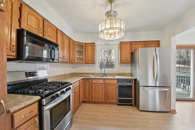 a kitchen with stainless steel appliances granite countertop a stove top oven a refrigerator a sink and dishwasher
