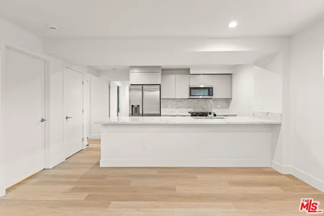 a view of kitchen with stainless steel appliances granite countertop white cabinets and window