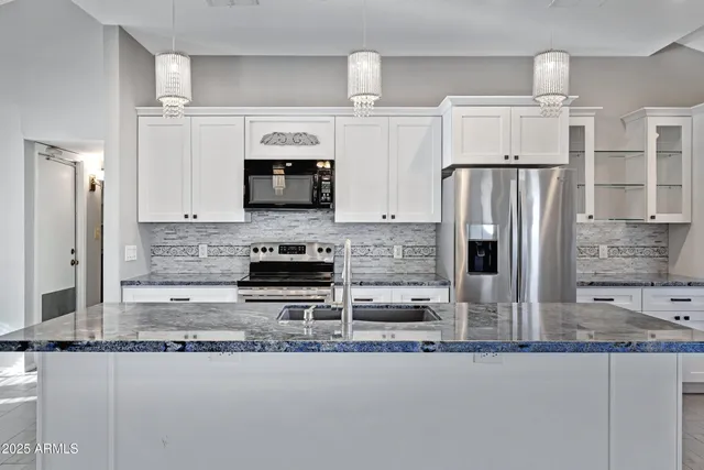 a kitchen with stainless steel appliances granite countertop a refrigerator and a stove top oven