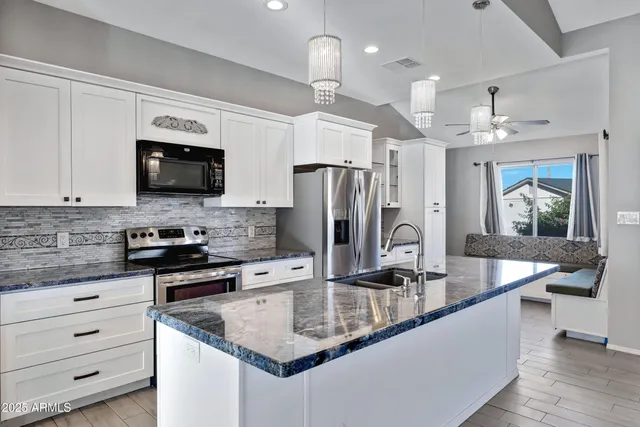 a kitchen with stainless steel appliances granite countertop a sink refrigerator and cabinets